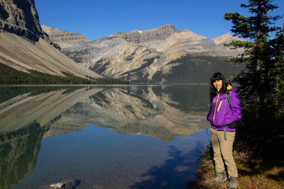 Rear view of woman standing against lake