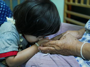 Granddaughter kissing hands of grandmother at home