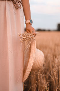 Midsection of bride holding wheat field