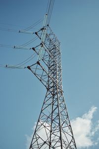 Low angle view of electricity pylon against blue sky