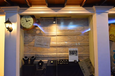 Illuminated lamp hanging on wall at restaurant