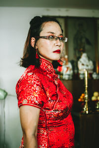 Portrait of young woman standing against wall