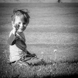 Portrait of boy showing flower on field