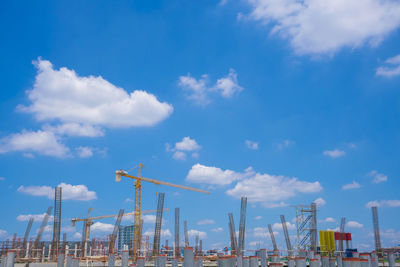 Low angle view of cranes against blue sky