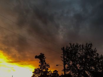 Low angle view of silhouette trees against dramatic sky