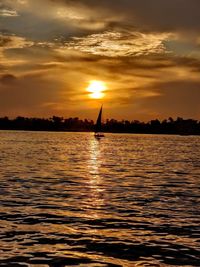 Silhouette man on sea against sky during sunset