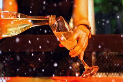 Midsection of woman holding champagne flute on table