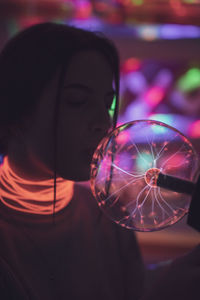 Close-up of woman kissing holding illuminated lighting equipment in room