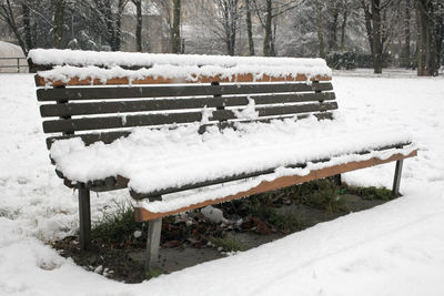 Snow covered bench in park during winter