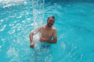 High angle view of shirtless man enjoying in swimming pool