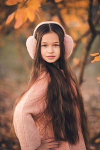 Cute kid girl 10-12 year old with long hair wear headband earphones yellow autumn leaves outdoor