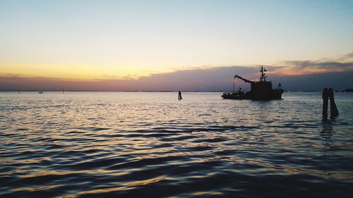 Silhouette ship in sea against sky during sunset
