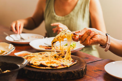 Woman hands taking slices of pizza with friends.
