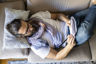 Man writing notes on couch in cozy living room