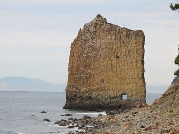 Rock formation on beach against sky