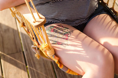 Midsection of woman sitting on swing chair at porch