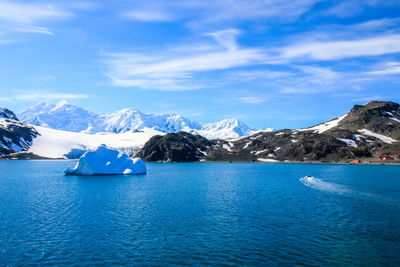 Scenic view of sea and snowcapped mountains against sky