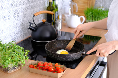 Woman frying scrambled eggs in a frying pan on a kitchen stove