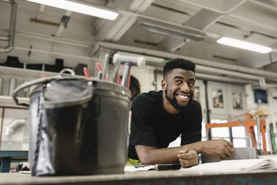 Smiling young male student looking away in workshop