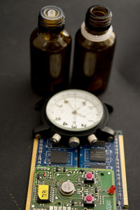 Close-up of circuit board and clock by bottles on table