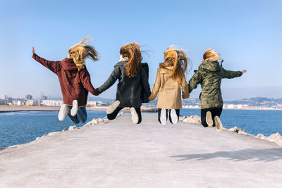 Back view of four friends jumping in the air