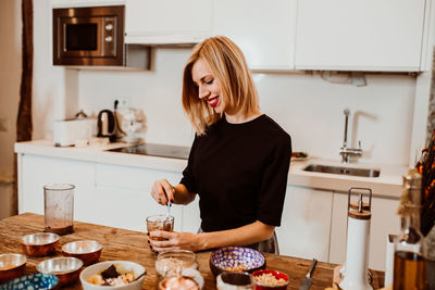 Young woman standing by table at home