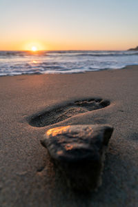 Surface level of beach against sky during sunset