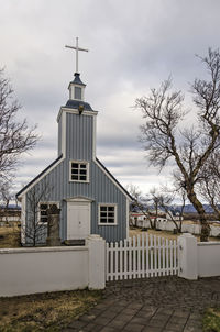 Front facade of the tiny wooden village church on the churchyard surrounded by a white fence