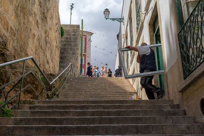 Low angle view of people on staircase amidst buildings in city