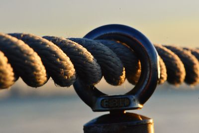 Close-up of rope tied on metal against sky