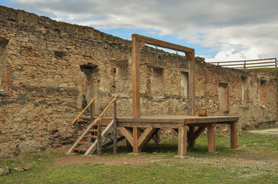 Old abandoned building on field against sky