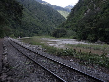 Railroad track by mountain against sky