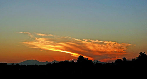Silhouette of landscape against cloudy sky at sunset