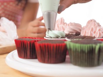 Cropped hand of woman preparing cupcakes at table