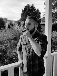 Portrait of young man standing against tree