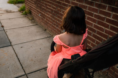 Little girl in orange dress riding in stroller