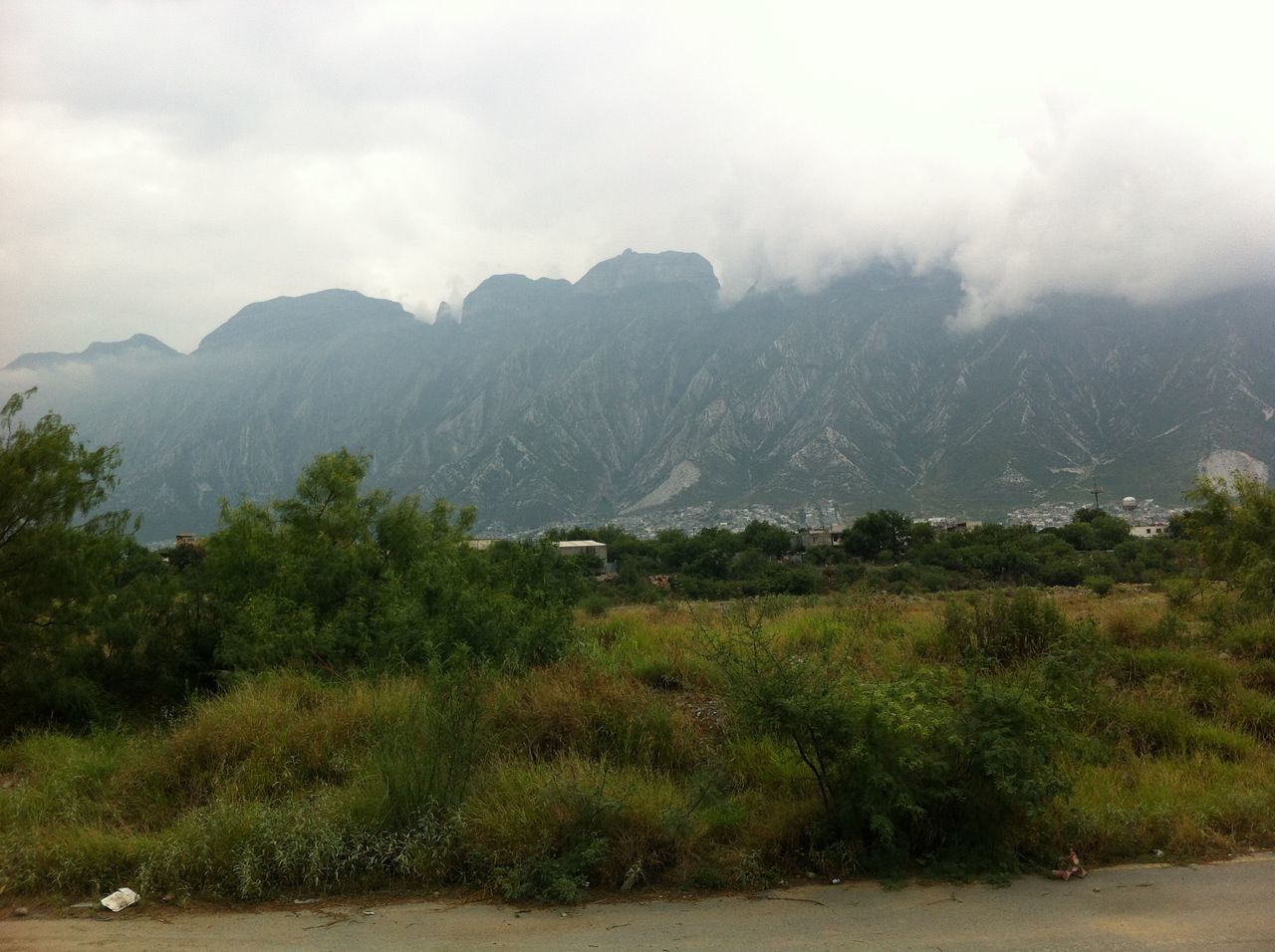 mountain, tranquil scene, sky, tranquility, scenics, beauty in nature, mountain range, landscape, nature, cloud - sky, non-urban scene, grass, tree, cloudy, idyllic, growth, remote, day, weather, outdoors