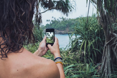 Rear view of man photographing through smart phone