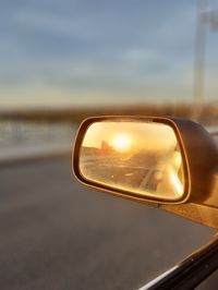 Reflection of cloudy sky on side-view mirror of car