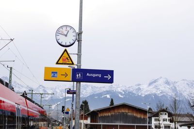 Road sign on snow covered mountain against sky