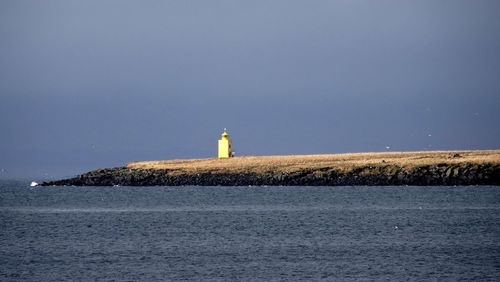 Lighthouse by sea against sky