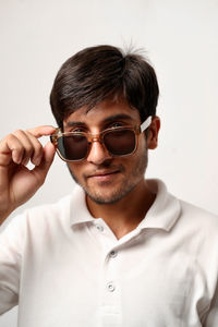 Portrait of young man wearing sunglasses against white background