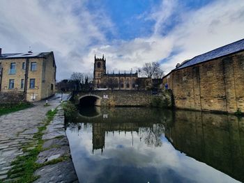 Canal by old building against sky