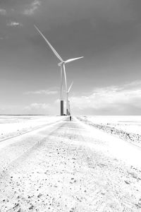 Windmills on land against sky