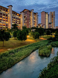 Buildings by river against sky