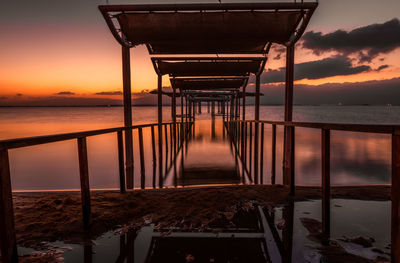 Pier over sea against sky during sunset