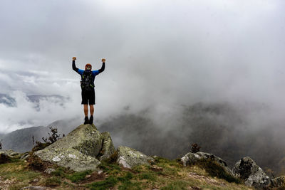 Rear view of man standing on mountain against sky