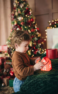 Side view of boy decorating christmas tree at home