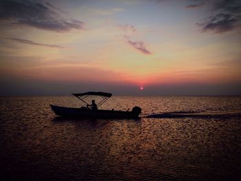 Silhouette boat in calm sea at sunset