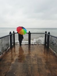 Woman standing on railing against sea during rainy season